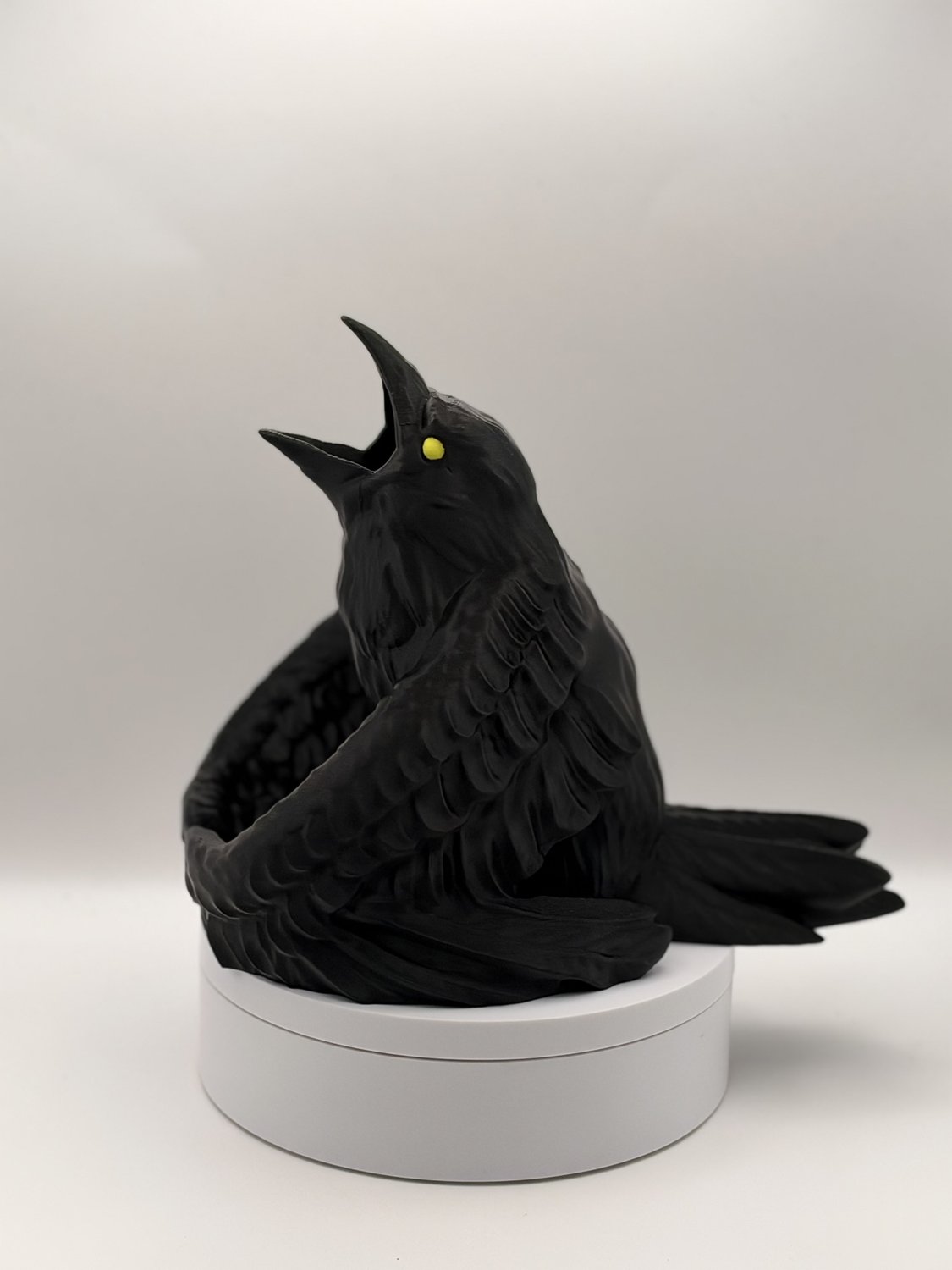 Side profile of black raven dice tower displaying detailed printed feathers